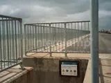 Steel handrails fitted on seaside beach front for pedestrian safety. Ocean in the distance and colourful seaside homes in the background 